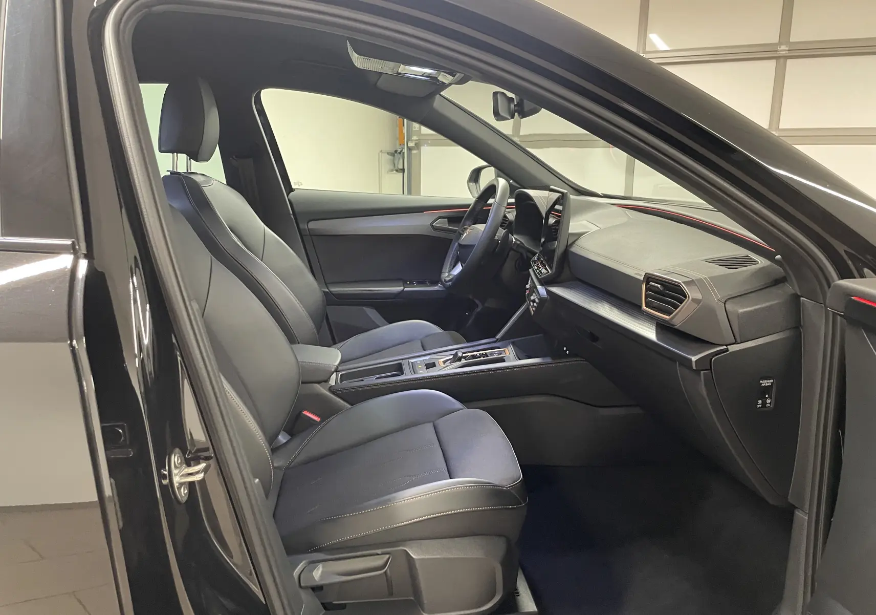 Intérieur avant droit d'un CUPRA Formentor Noir Minuit 2025, sièges en cuir noir et tableau de bord moderne avec écran tactile.