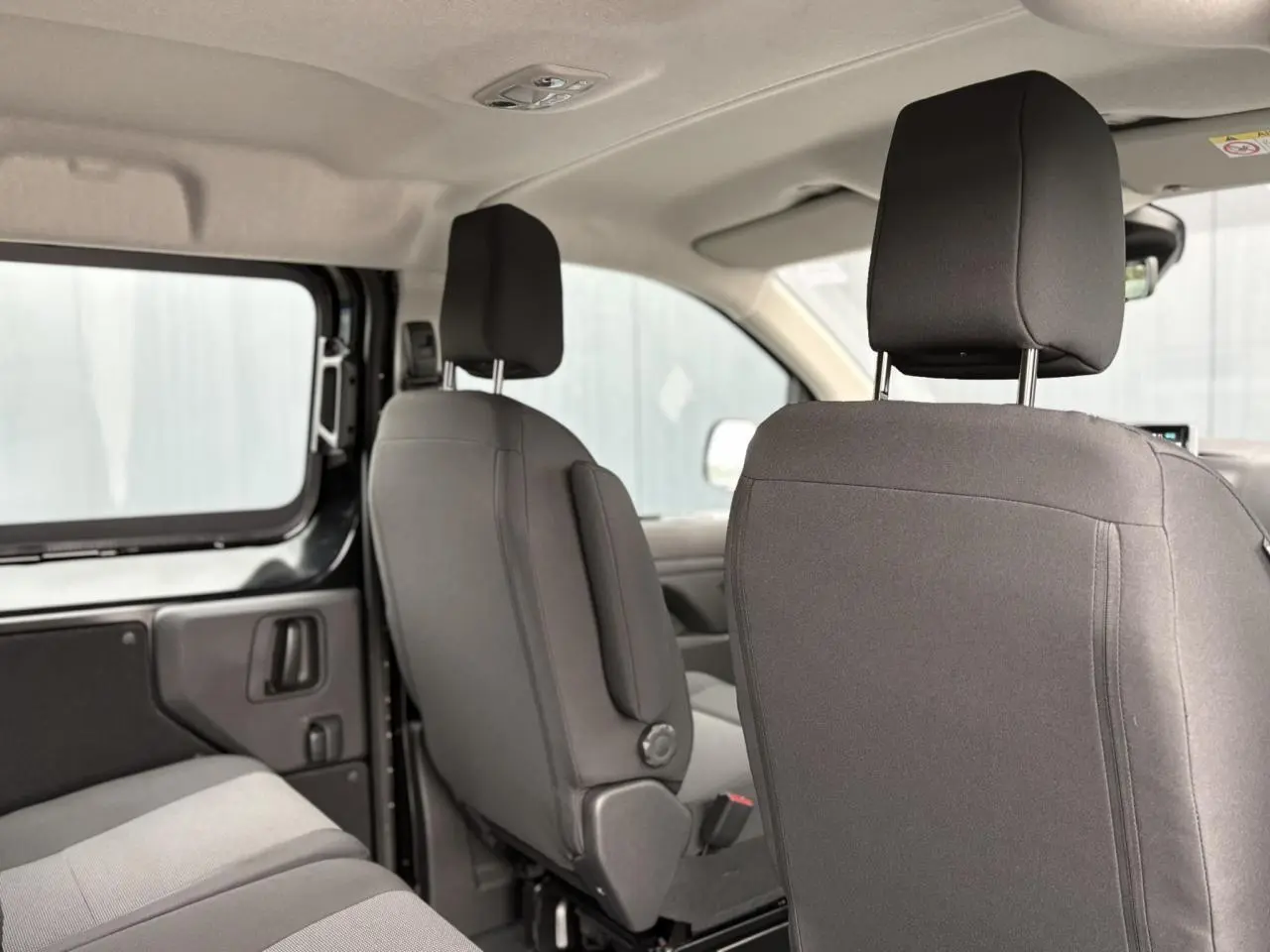 Vue intérieure côté gauche du Citroën Jumpy XL 2025 noir Perla, montrant les sièges avant et banquette arrière tissu bi-ton.