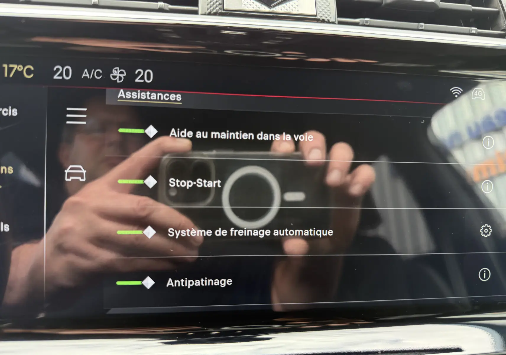 Écran tactile intérieur du DS7 2025 affichant les assistances à la conduite, avec reflet des mains et du smartphone.