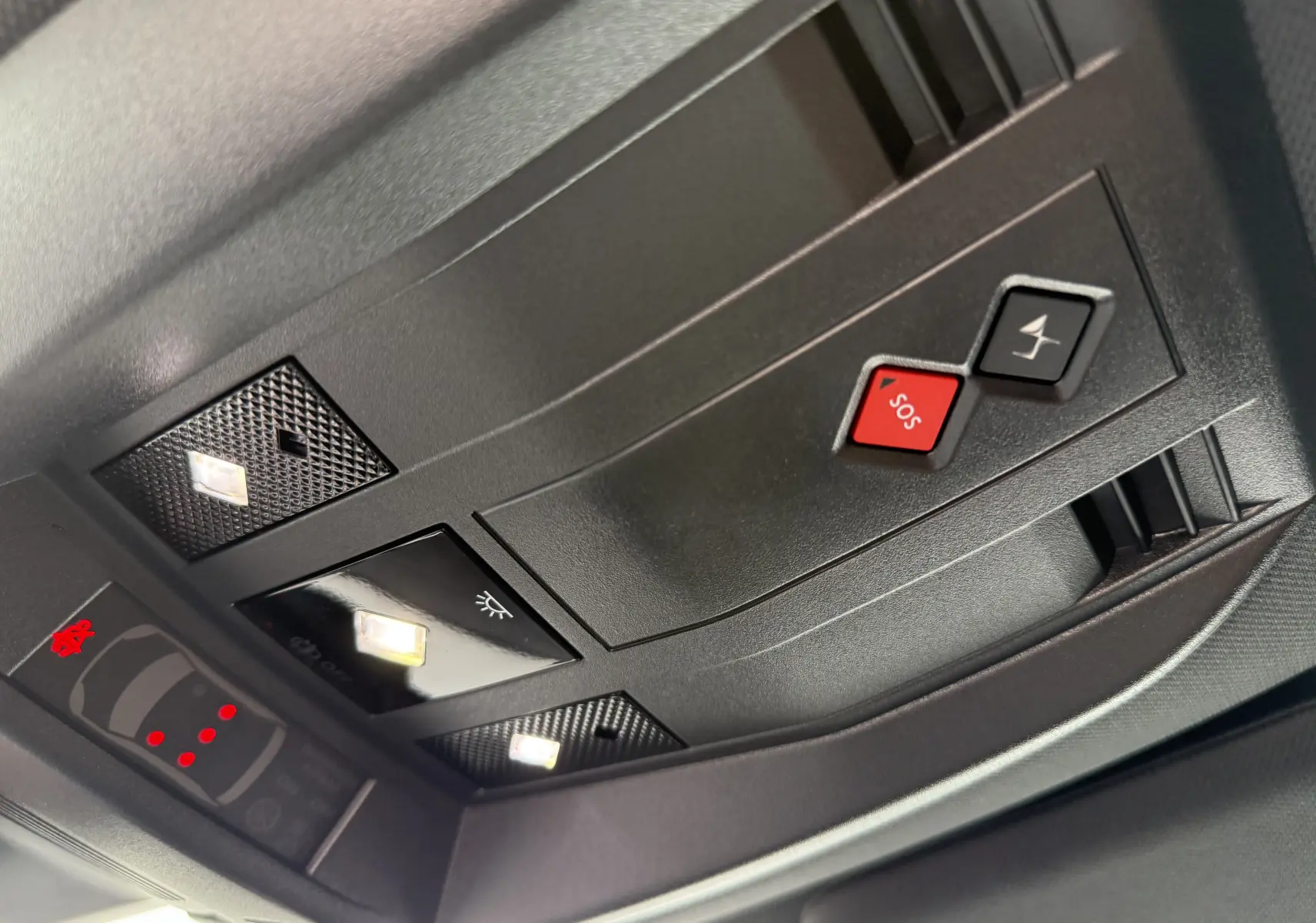 Vue en gros plan du plafonnier intérieur noir du DS7 2025 avec boutons SOS et assistance, éclairage LED intégré.