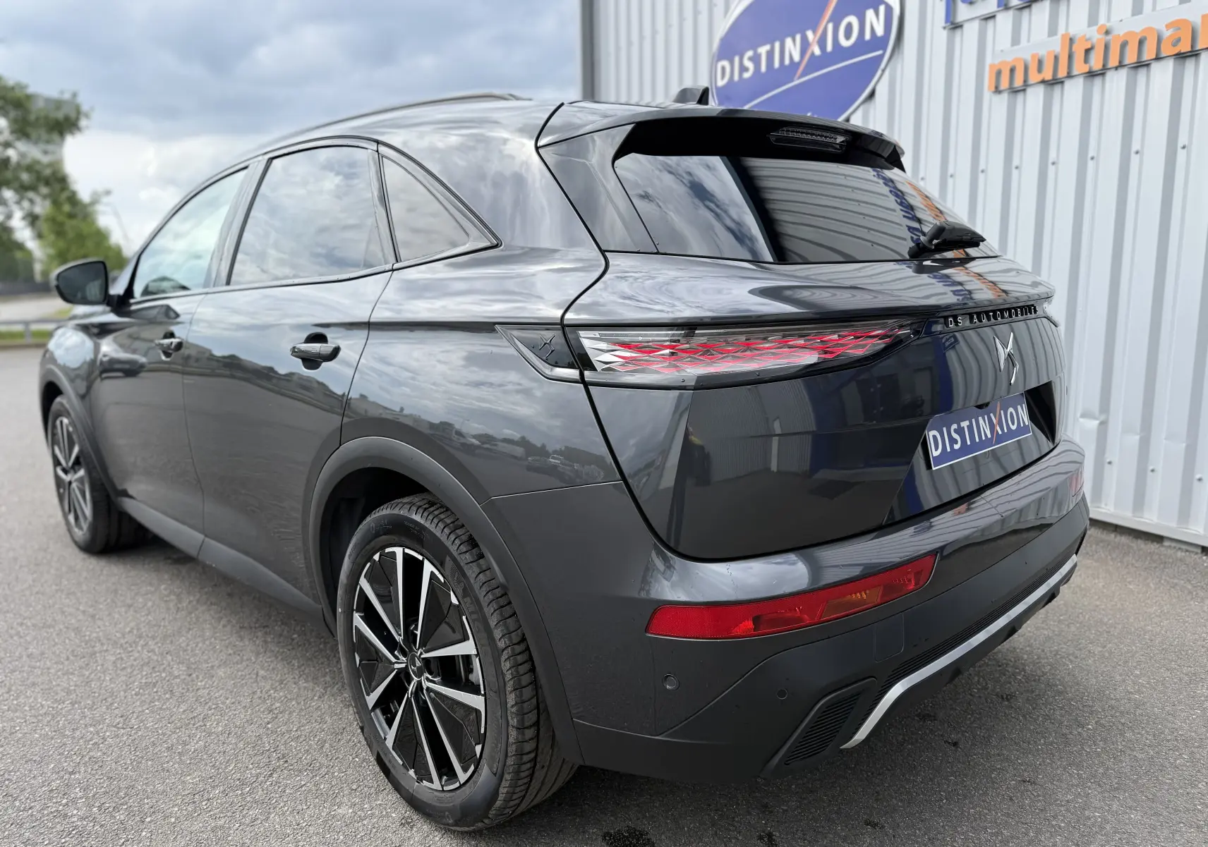 Vue 3/4 arrière droite d'un DS7 BlueHDi 130 gris titane avec feux arrière LED et jantes alliage bicolores.