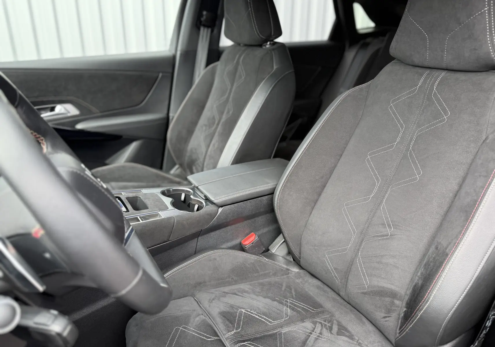Vue intérieure côté conducteur du DS7 2025 gris titane, sièges en cuir et alcantara avec surpiqûres contrastées.