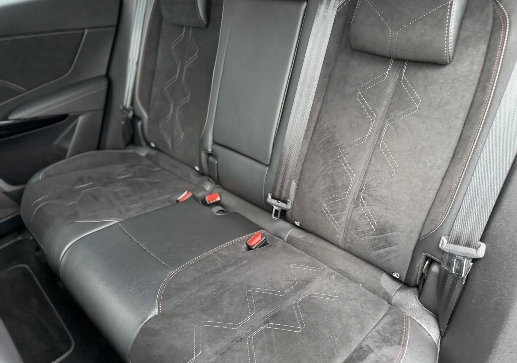 Vue rapprochée des sièges arrière en cuir et alcantara noir avec surpiqûres rouges du DS7 BlueHDi 130 Pallas 2025.