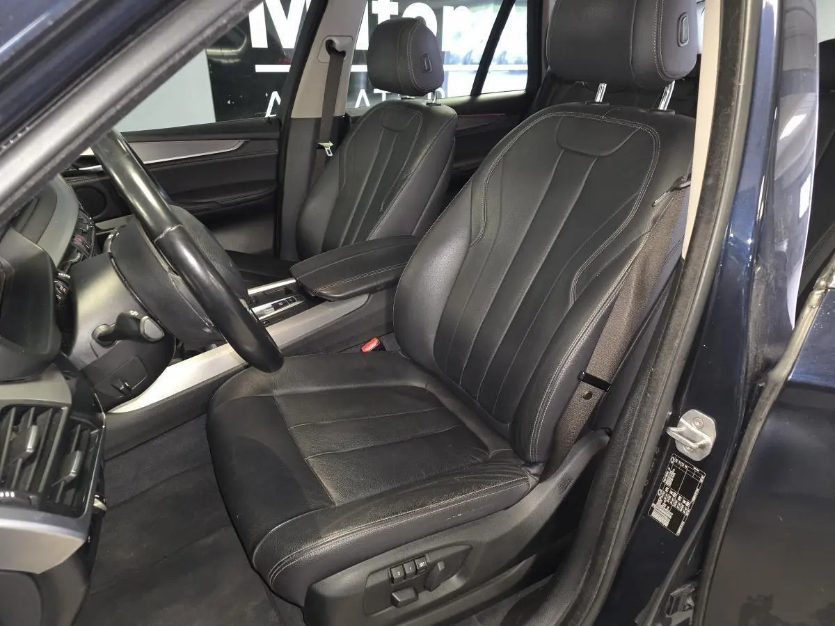 Vue intérieure côté conducteur du BMW X5 sDrive 25d 2018 bleu, mettant en valeur la sellerie cuir Dakota noire et les sièges électriques.