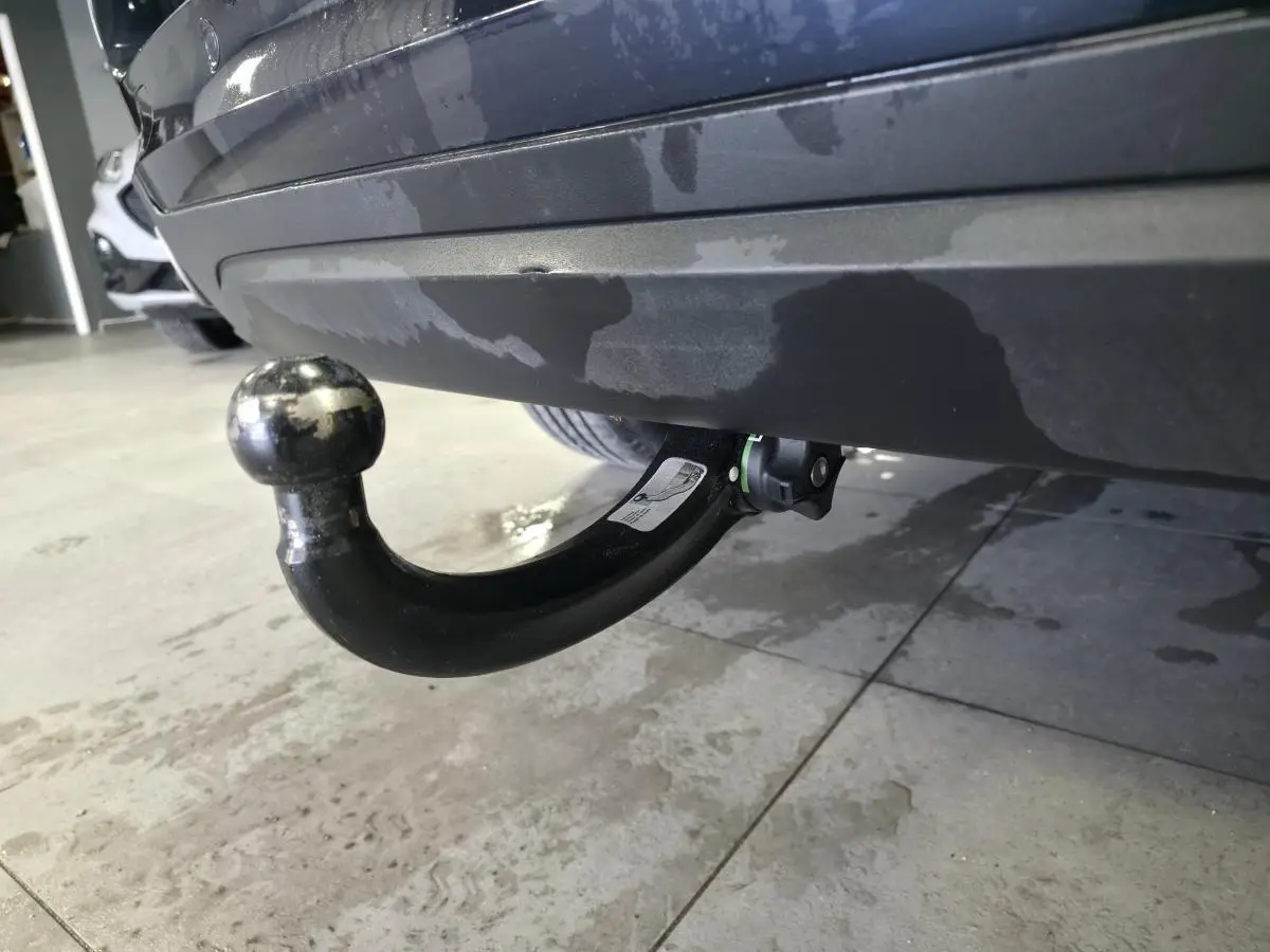 Gros plan sur le crochet d'attelage noir démontable sous le pare-chocs arrière bleu métallisé du BMW X5 sDrive 25d.