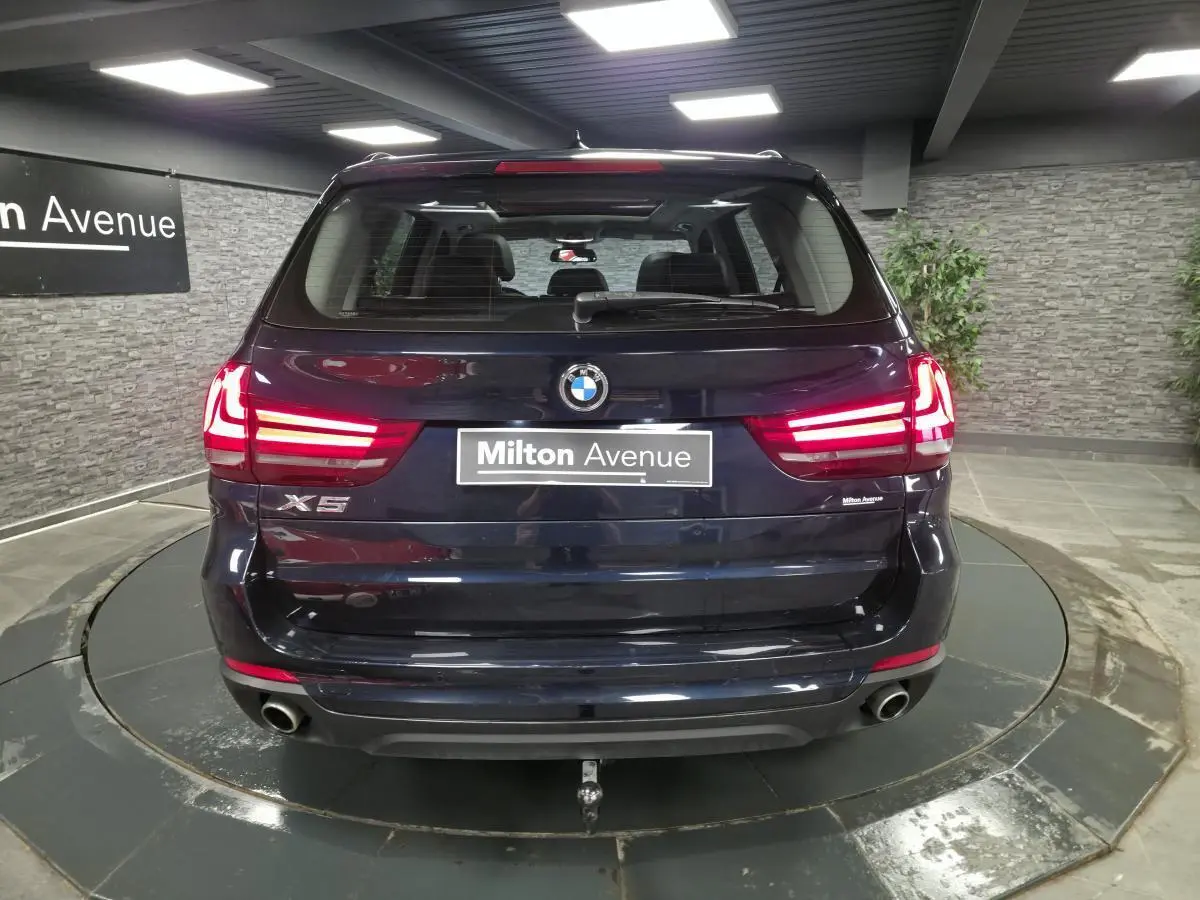 Vue arrière d'un BMW X5 sDrive 25d bleu métallisé avec feux LED allumés et crochet d'attelage démontable.
