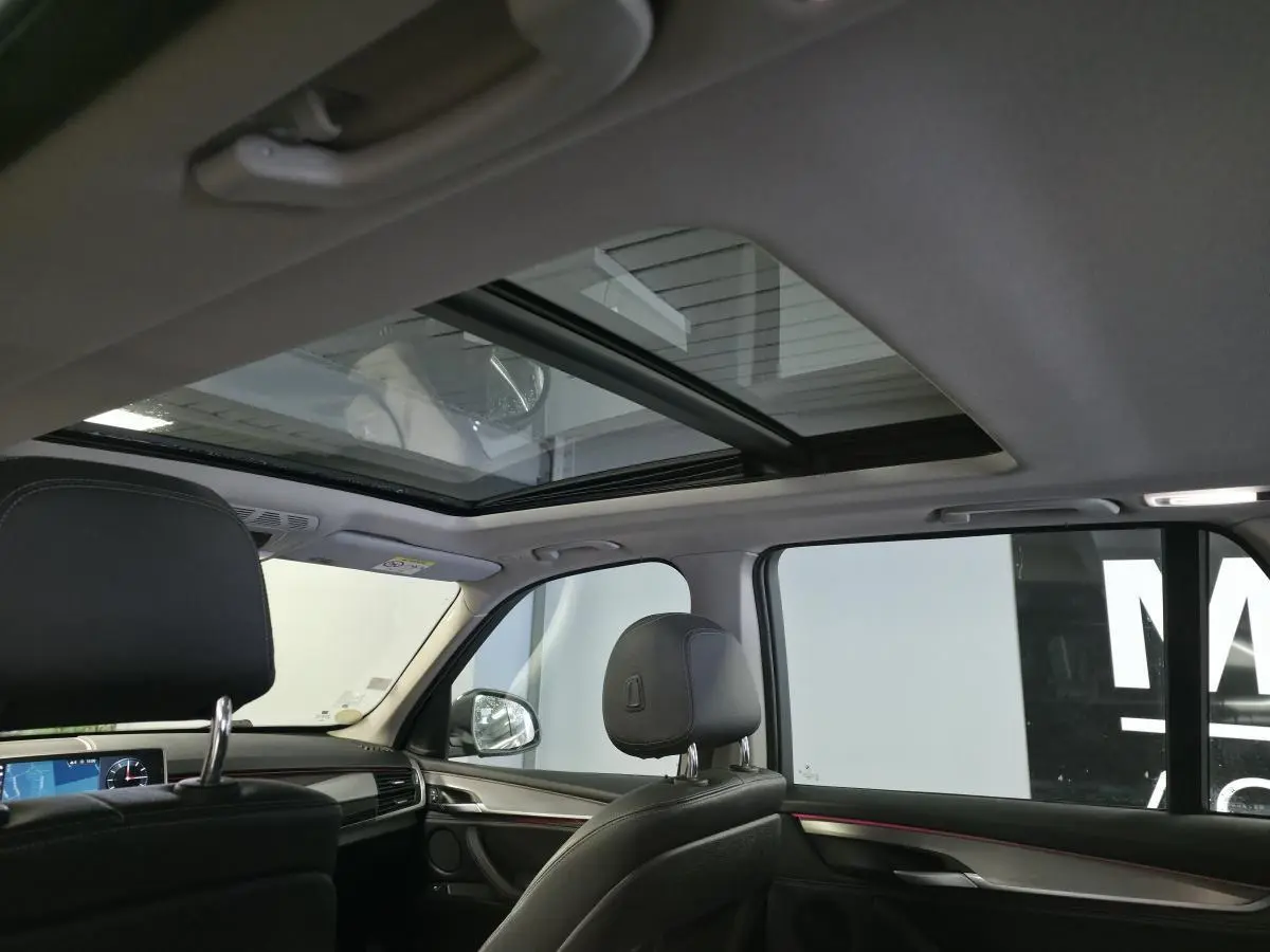 Vue intérieure du toit ouvrant panoramique en verre et des sièges avant en cuir noir du BMW X5 sDrive 25d 2018.
