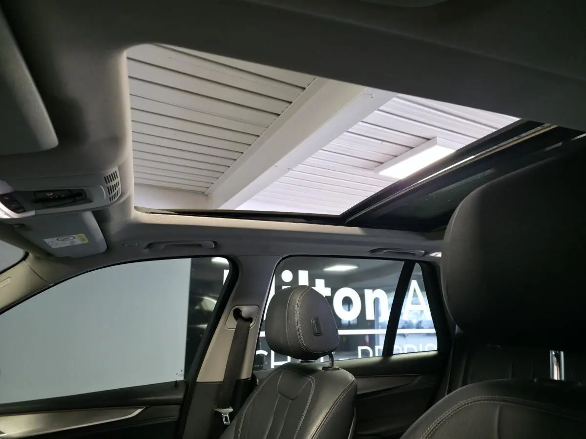 Vue intérieure du BMW X5 sDrive 25d 2018 montrant la sellerie cuir noire et le toit ouvrant panoramique en verre.