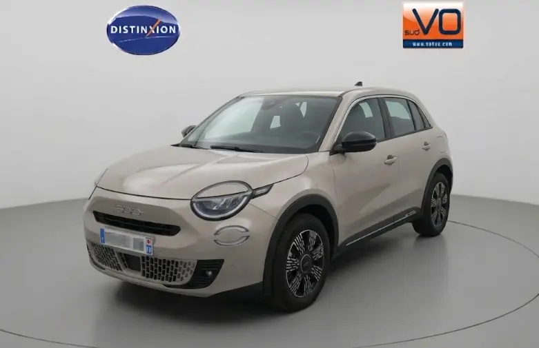 Vue 3/4 avant d'une FIAT 600 beige 2025 avec phares antibrouillard et pack chrome visible sur la calandre et les jantes.