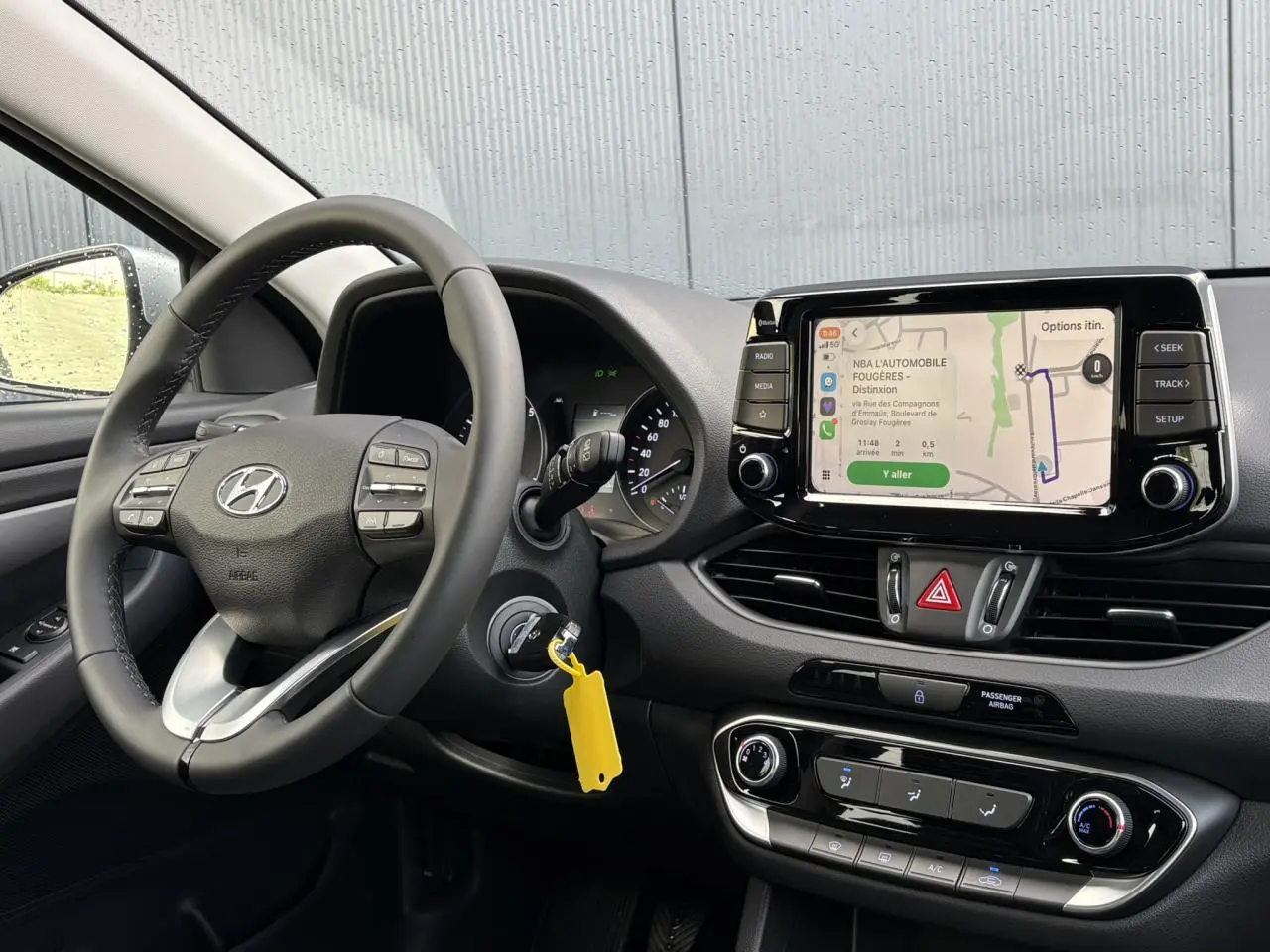 Vue intérieure côté conducteur de la Hyundai i30 SW T-GDI 120 Modern 2025, tableau de bord noir avec écran tactile et volant cuir.