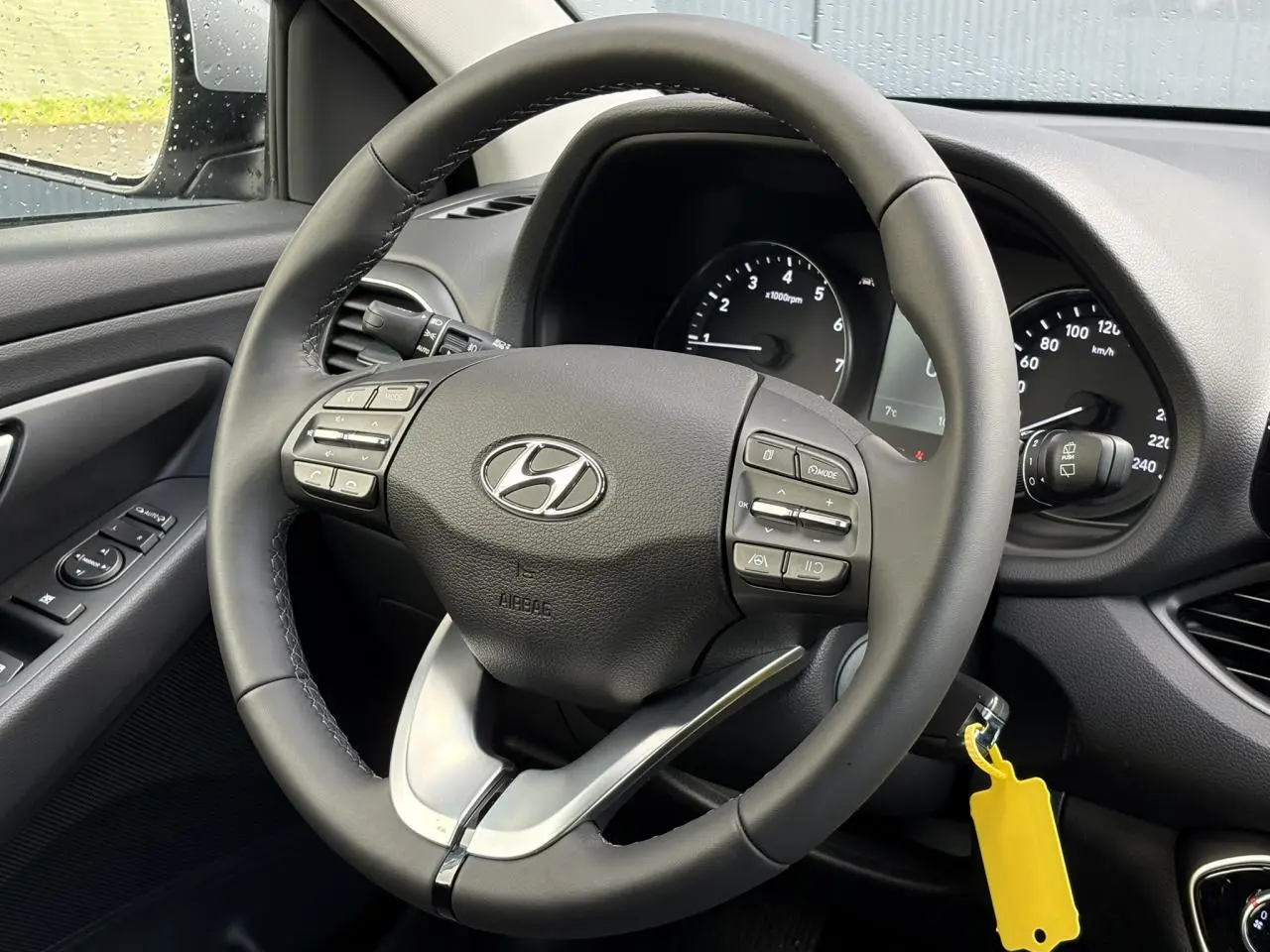 Vue rapprochée du volant cuir noir de la Hyundai i30 SW T-GDI 120 Modern avec commandes intégrées et tableau de bord visible.