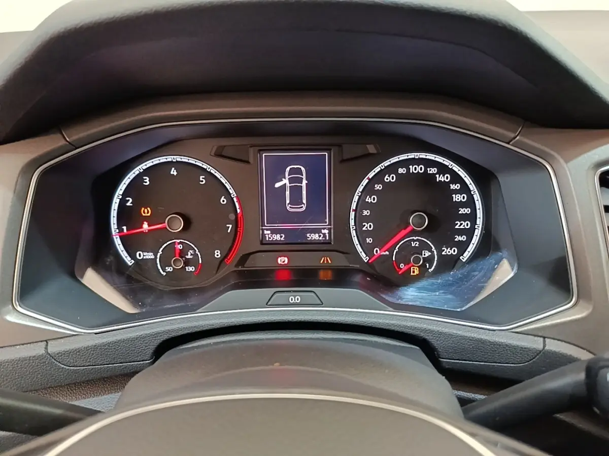 Vue rapprochée du tableau de bord numérique du Volkswagen T-Roc 1.5 TSI bleu, affichant les compteurs et alertes.