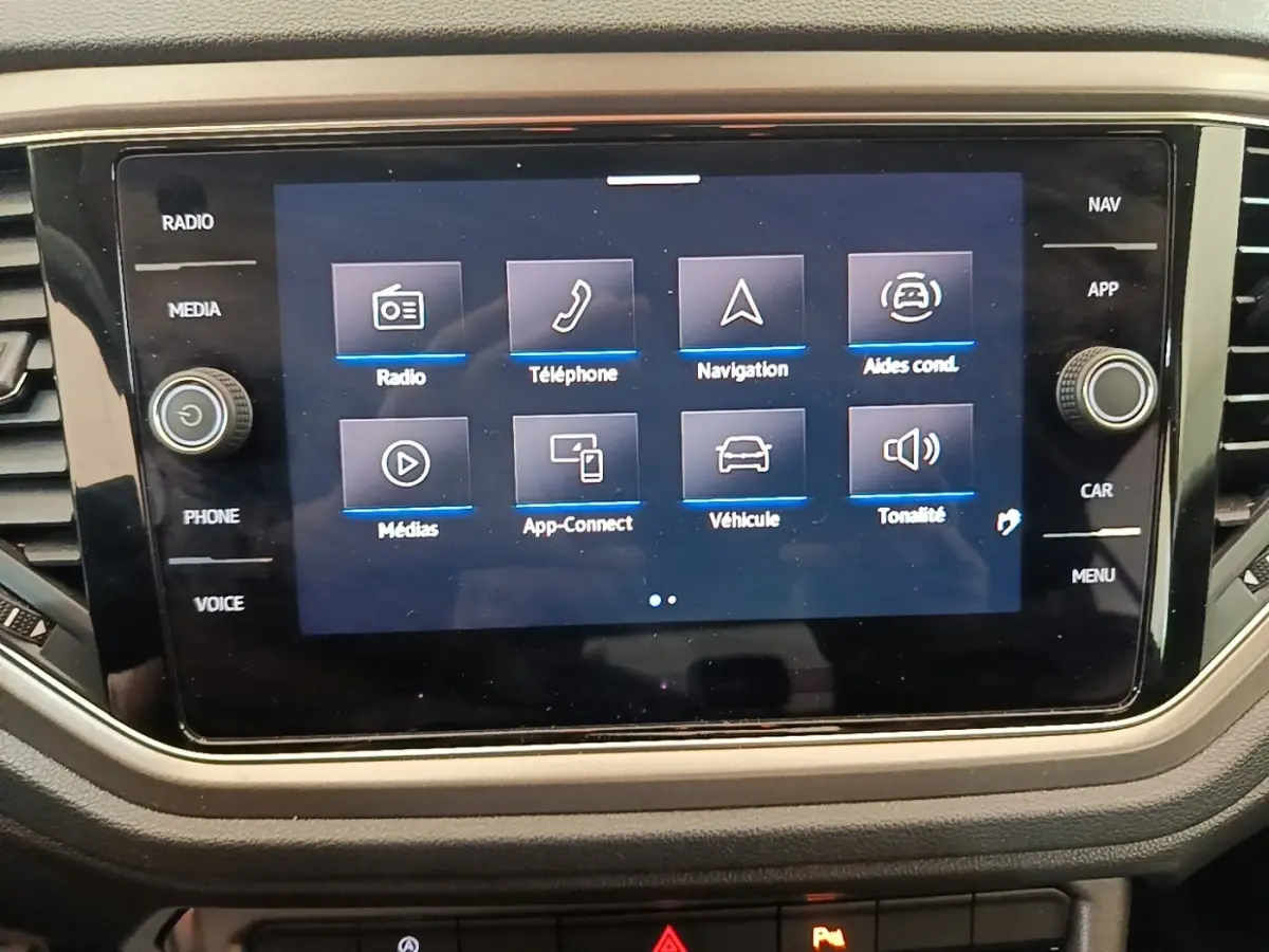 Écran tactile central du Volkswagen T-Roc bleu 2020 affichant les options radio, téléphone, navigation et aides à la conduite.