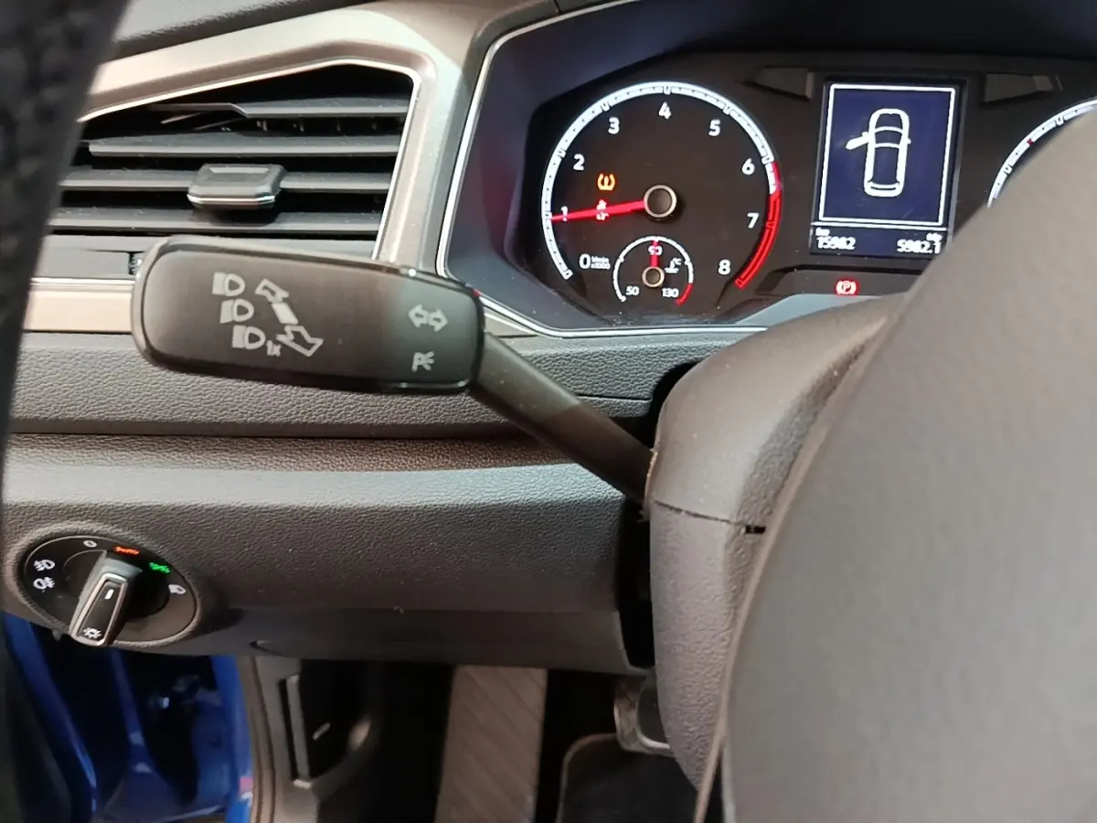Vue rapprochée du tableau de bord et du commodo gauche du Volkswagen T-Roc bleu, avec compteurs et voyants visibles.