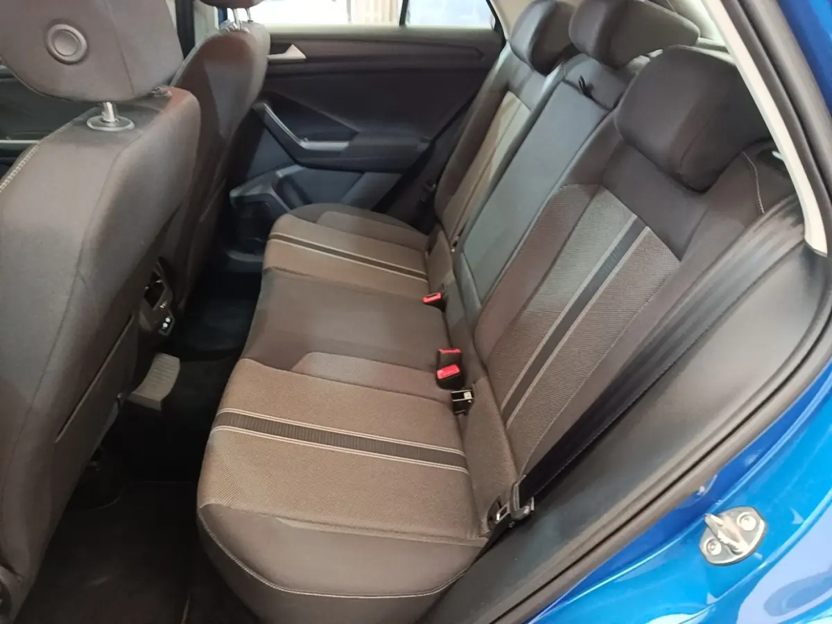 Vue intérieure côté arrière droit du Volkswagen T-Roc bleu 2020, montrant la banquette arrière en tissu gris à motifs rayés.