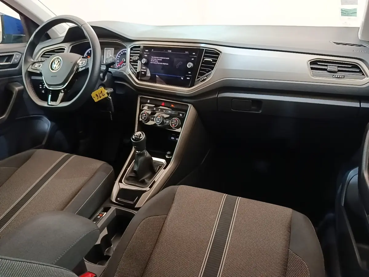 Vue intérieure avant du Volkswagen T-Roc 1.5 TSI 2020, montrant le volant cuir, tableau de bord digital et boîte manuelle.