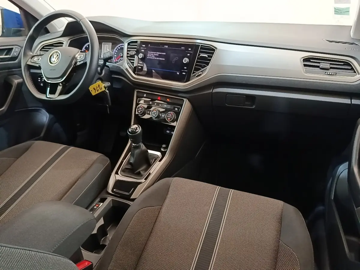 Vue intérieure avant du Volkswagen T-Roc 1.5 TSI 2020, montrant le volant cuir, tableau de bord et levier de vitesse manuel.