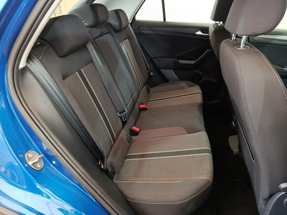 Vue intérieure côté arrière droit du Volkswagen T-Roc bleu, montrant la banquette arrière en tissu gris avec détails rayés.