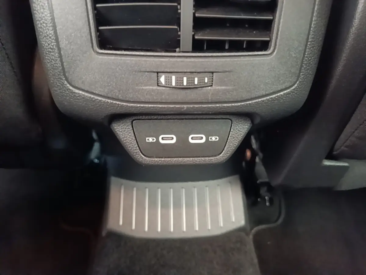 Vue rapprochée des ports USB-C doubles et de la sortie d'air arrière dans l'habitacle noir du Volkswagen T-Roc bleu.