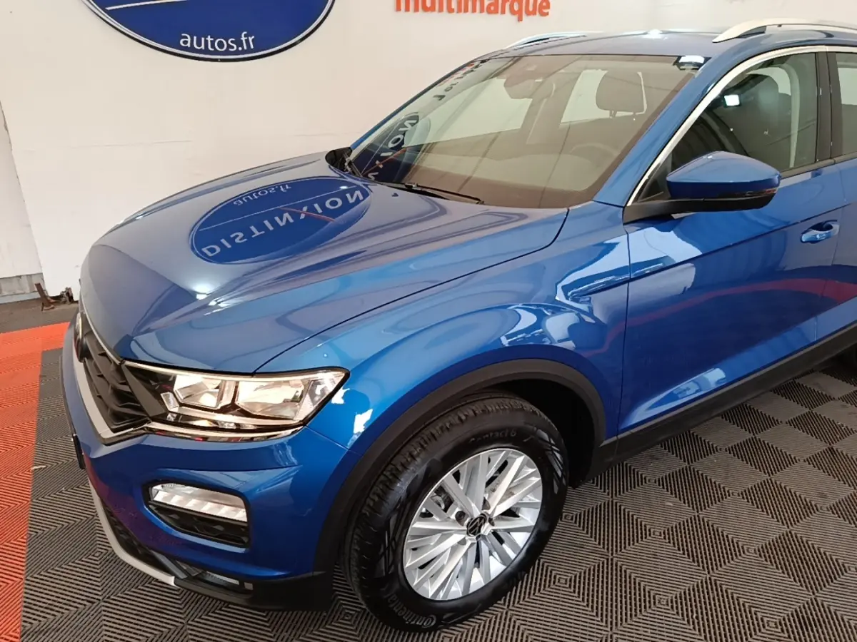 Vue 3/4 avant droit d'un Volkswagen T-Roc bleu brillant avec jantes alliage et rétroviseurs assortis.
