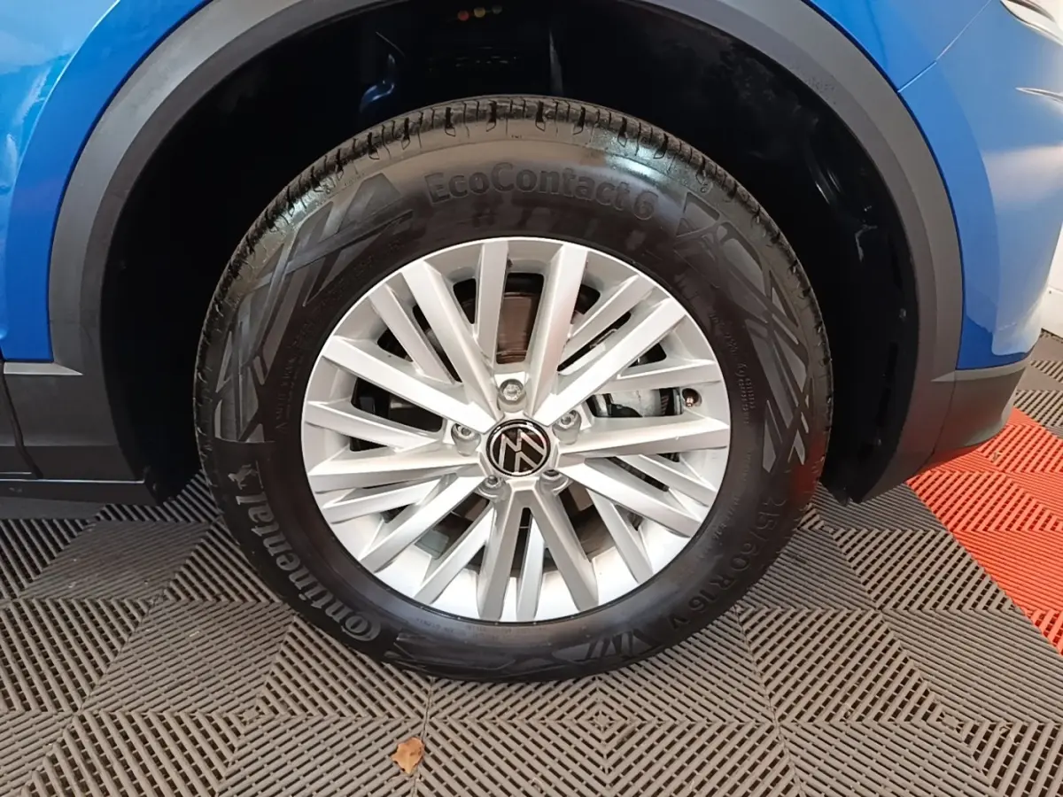 Gros plan sur la roue avant droite d’un Volkswagen T-Roc bleu, mettant en valeur la jante alliage et le pneu Continental.