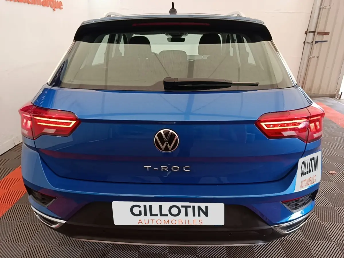 Vue arrière d'un Volkswagen T-Roc bleu 2020 avec feux LED allumés et logo VW bien visible.