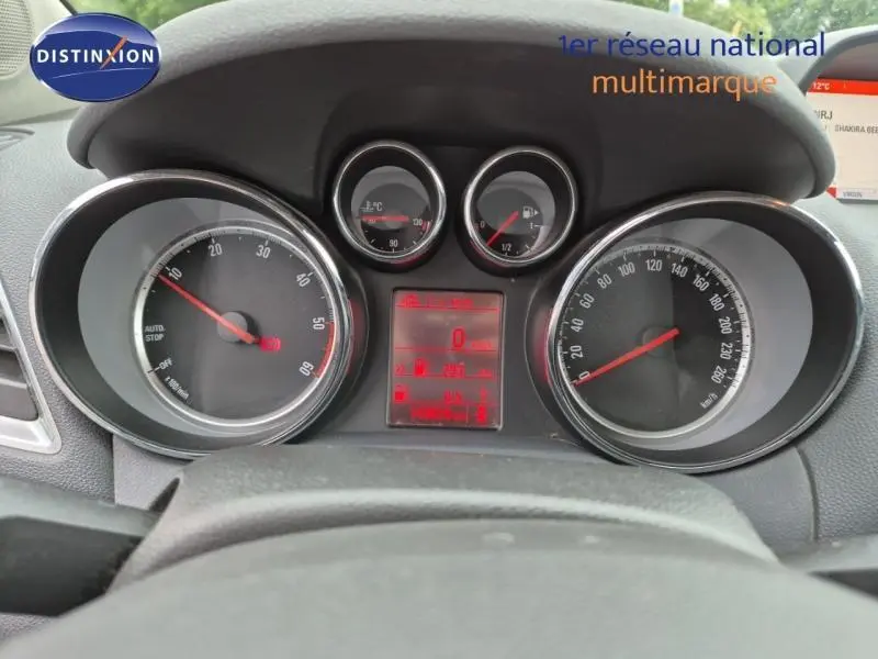 Vue rapprochée du tableau de bord de l'Opel Mokka 2015, affichage numérique rouge et compteurs analogiques.