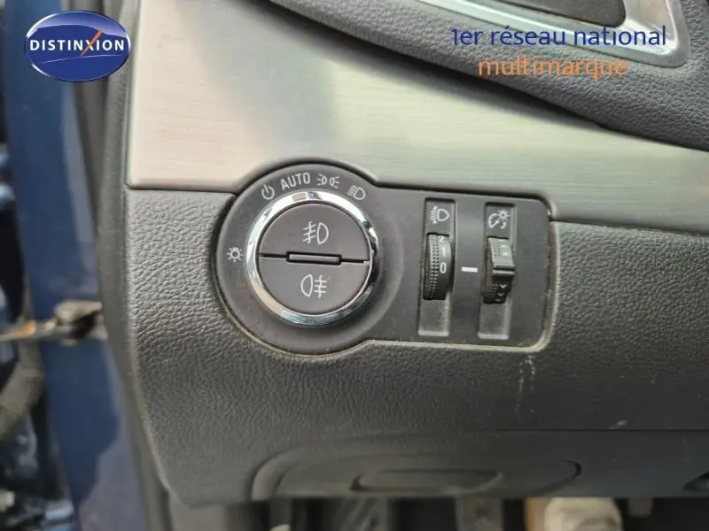 Gros plan sur le bouton de commande des phares et réglages lumineux dans un Opel Mokka bleu outremer de 2015.