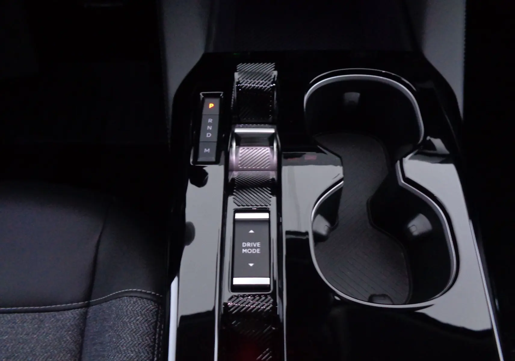 Gros plan sur la console centrale noire brillante de la Citroën C5 X 2023, avec levier de vitesses automatique et porte-gobelets.