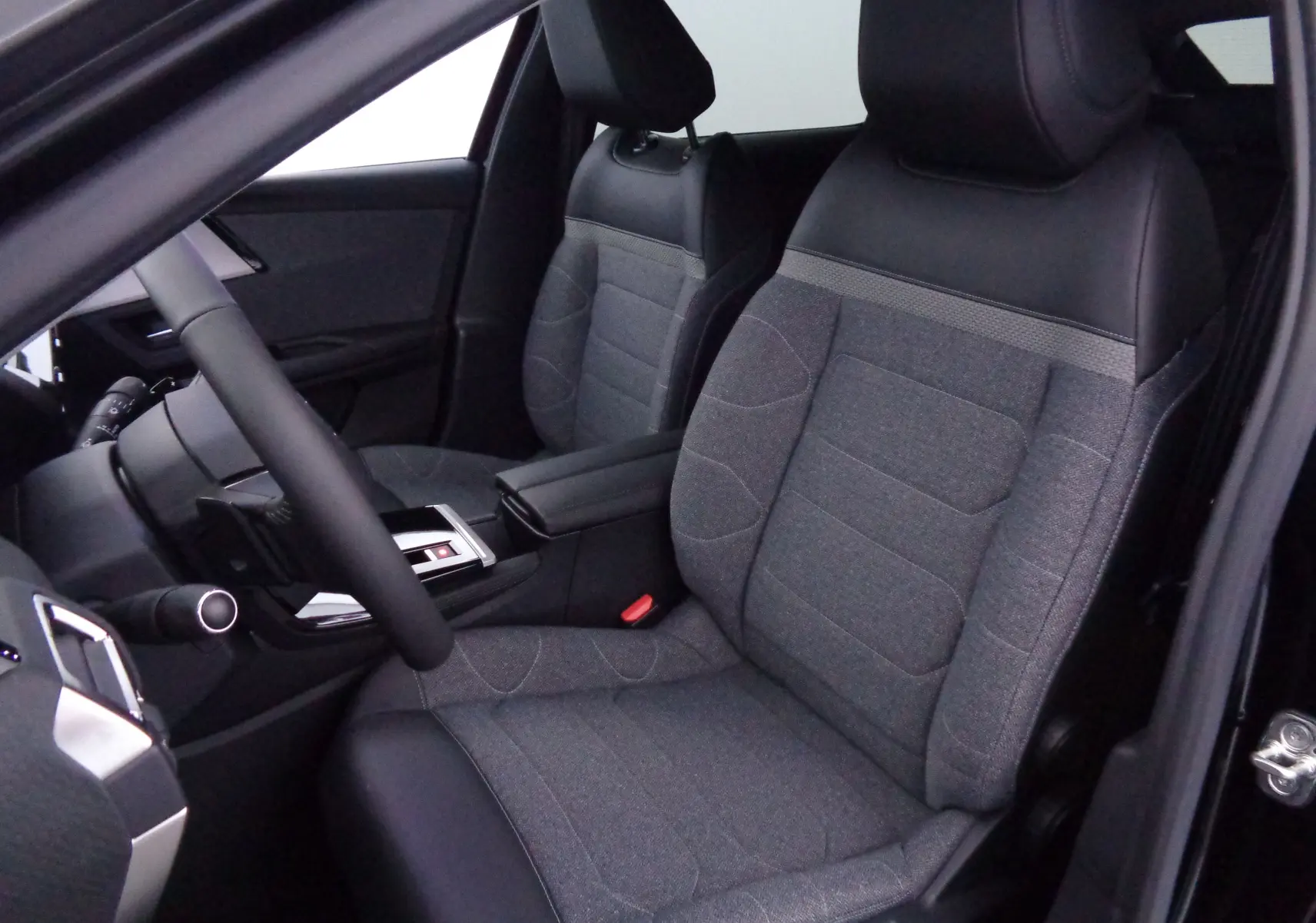 Intérieur avant droit de la Citroën C5 X 2023 avec sièges bi-matière gris et noir et volant visible.