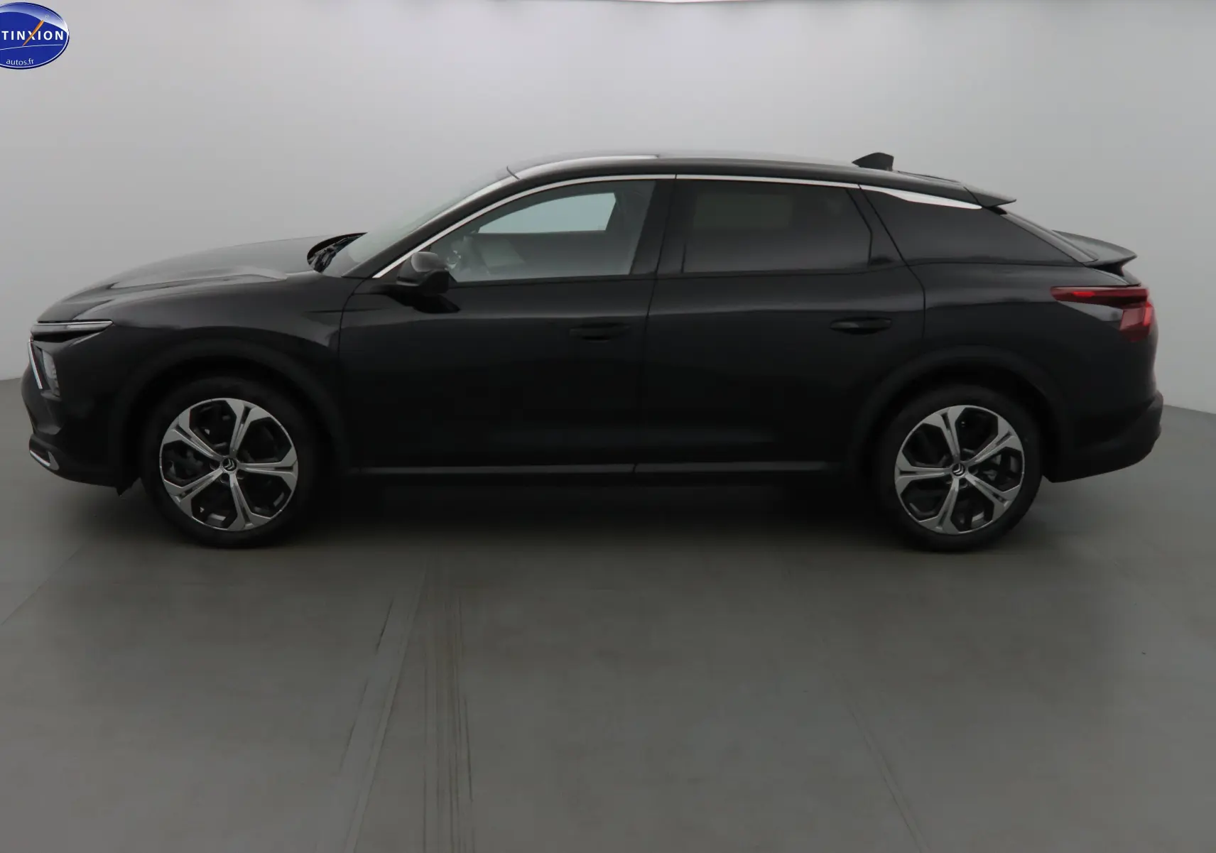 Profil côté gauche d'une Citroën C5 X noire métal 2023 avec toit contrasté gris et jantes bi-ton distinctives.