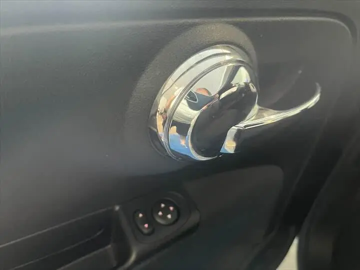 Poignée de porte intérieure chromée et commandes de réglage des rétroviseurs sur FIAT 500 blanc, vue côté conducteur.