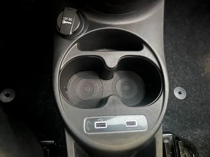 Gros plan sur les porte-gobelets et les deux ports USB du compartiment central d'une FIAT 500 blanche de 2023.