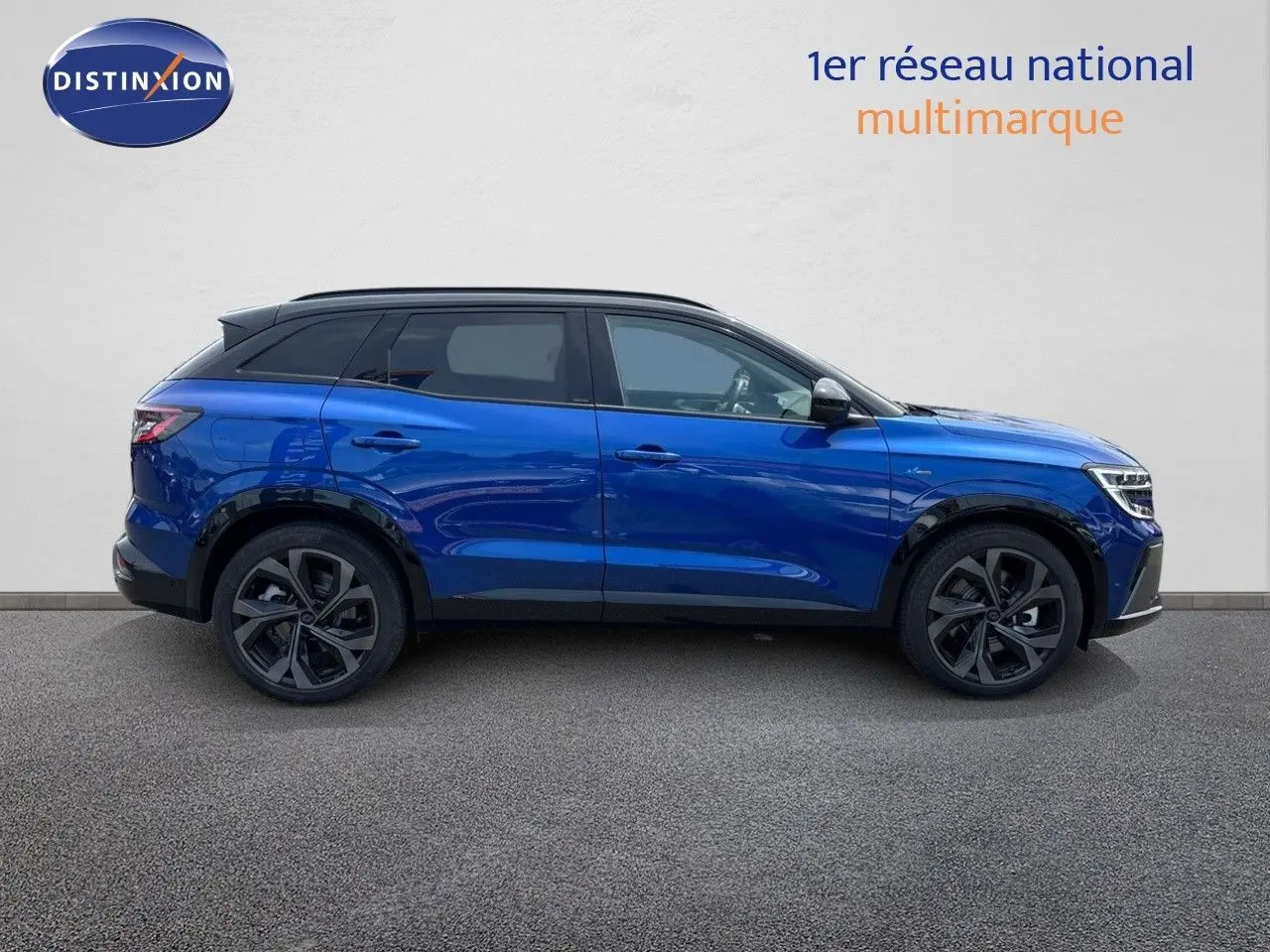 Profil droit d'un Renault Austral E-Tech hybride bleu Iron Metal avec toit noir, soulignant ses jantes noires et lignes modernes.