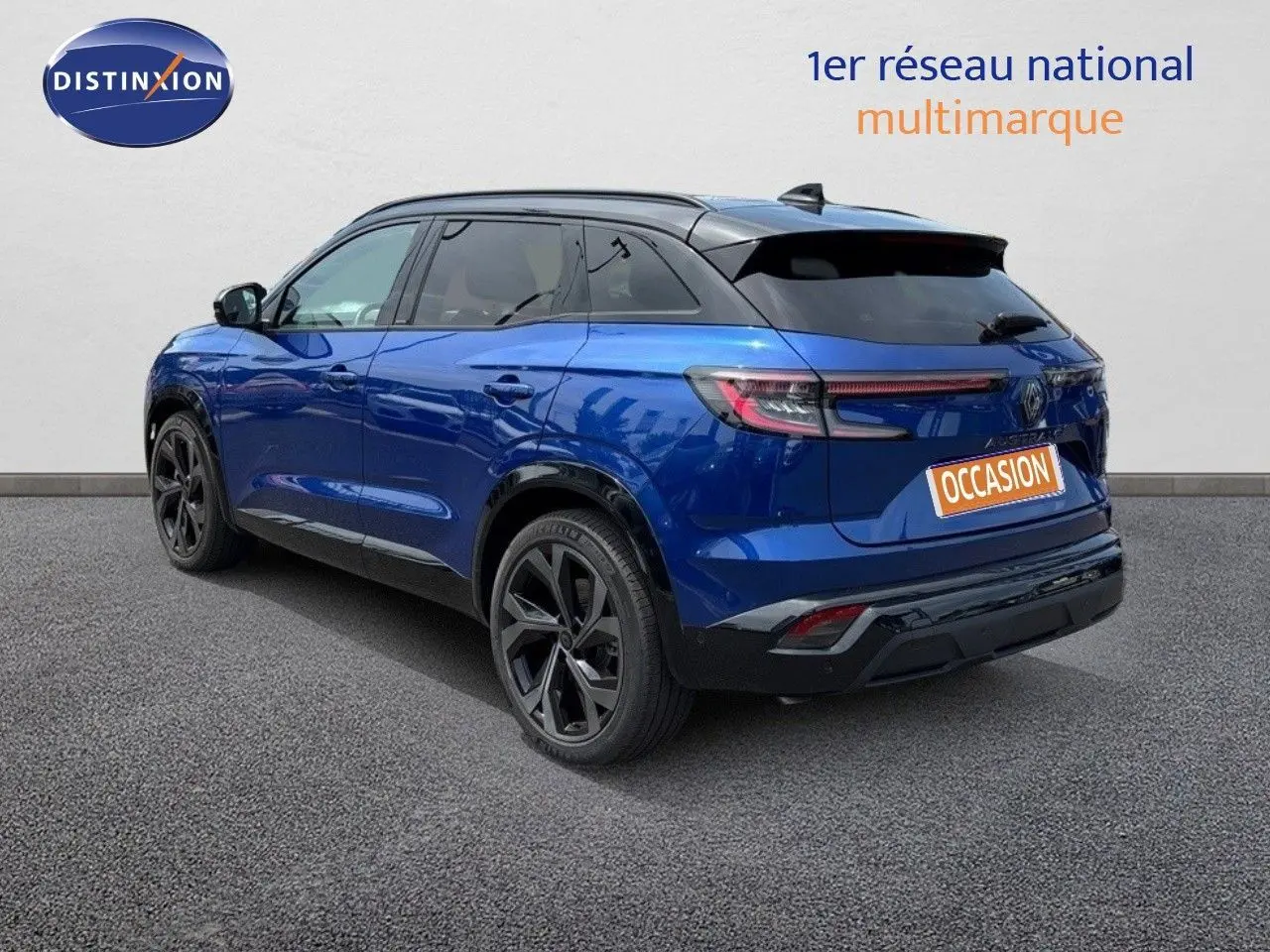 Vue 3/4 arrière d'un Renault Austral bleu Iron Metal avec toit noir et jantes noires sur fond neutre.