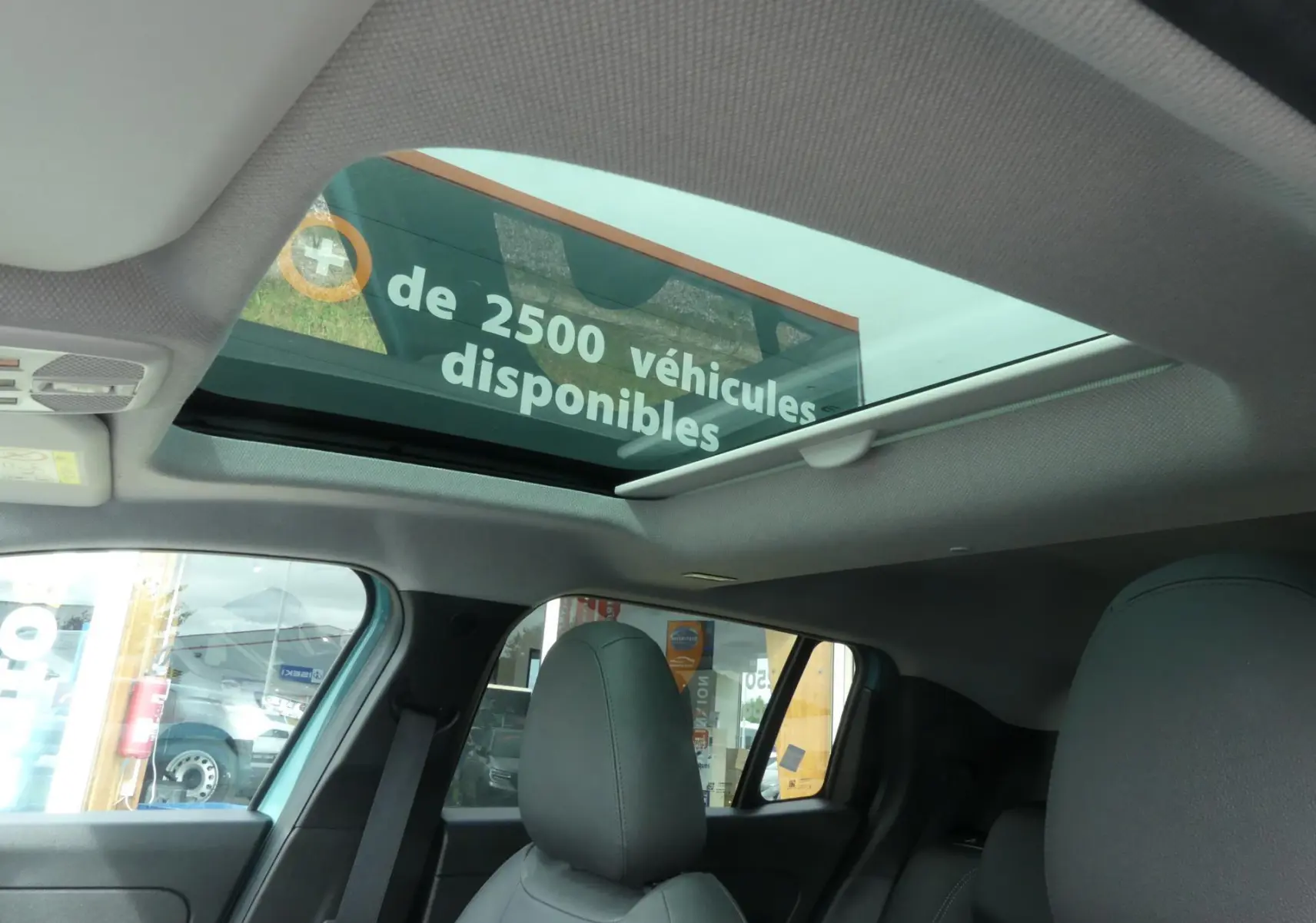 Toit ouvrant électrique en verre vu de l'intérieur arrière d'un Jeep Avenger bleu métallisé 2024