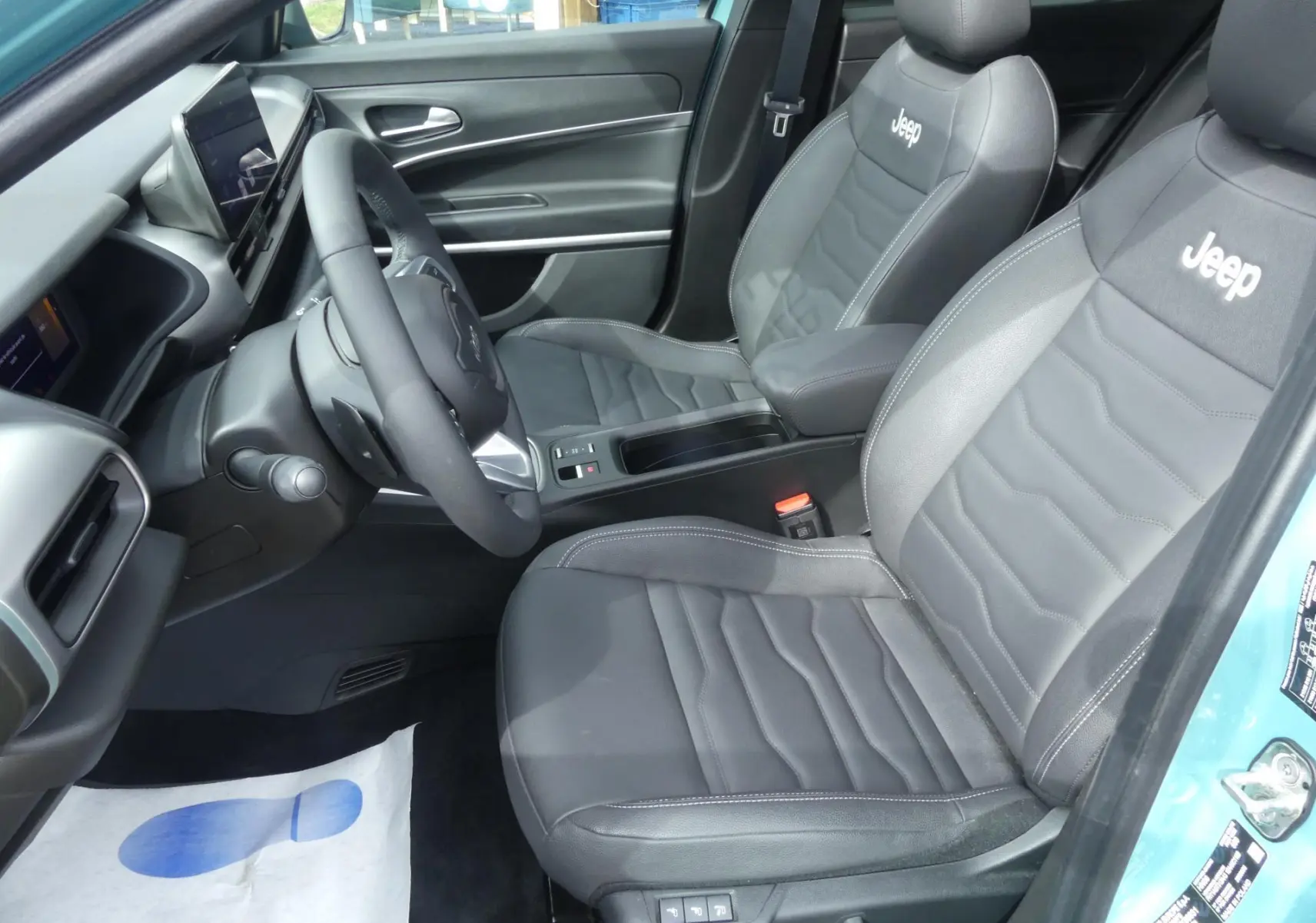 Intérieur avant droit du Jeep Avenger 2024 avec sièges cuir noir brodés Jeep et tableau de bord moderne.