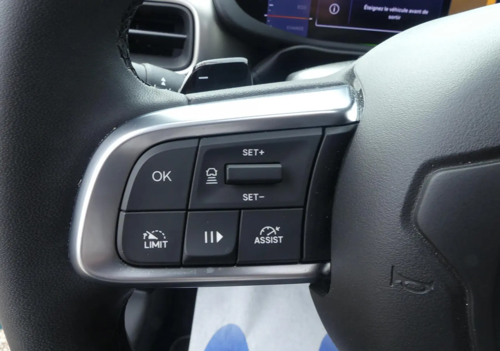 Gros plan sur les commandes du volant à gauche du Jeep Avenger 2024, finition Summit, avec boutons de régulateur et assistance.