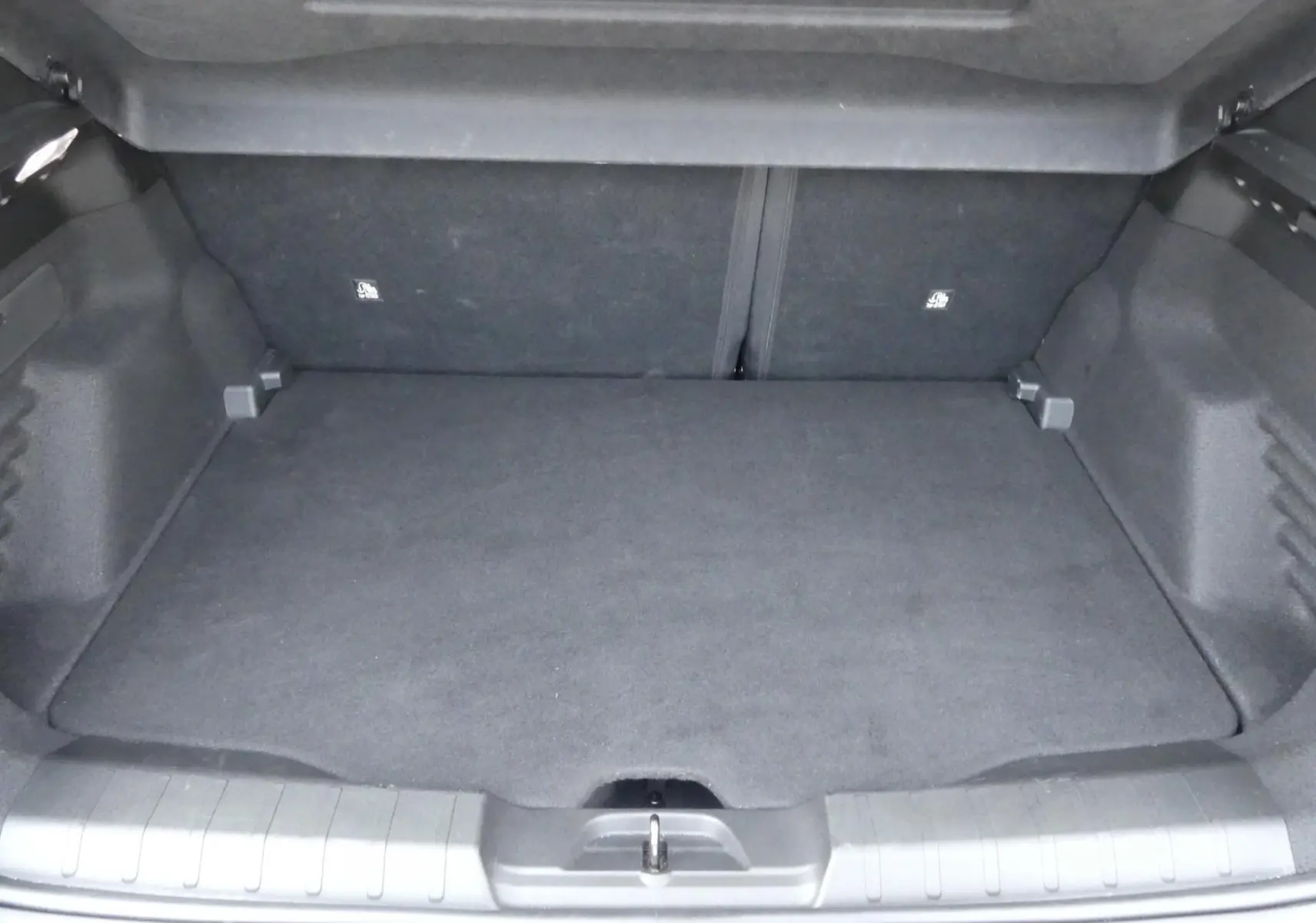 Coffre ouvert du Jeep Avenger 2024, vue arrière, espace de chargement noir et tapis de sol plat.