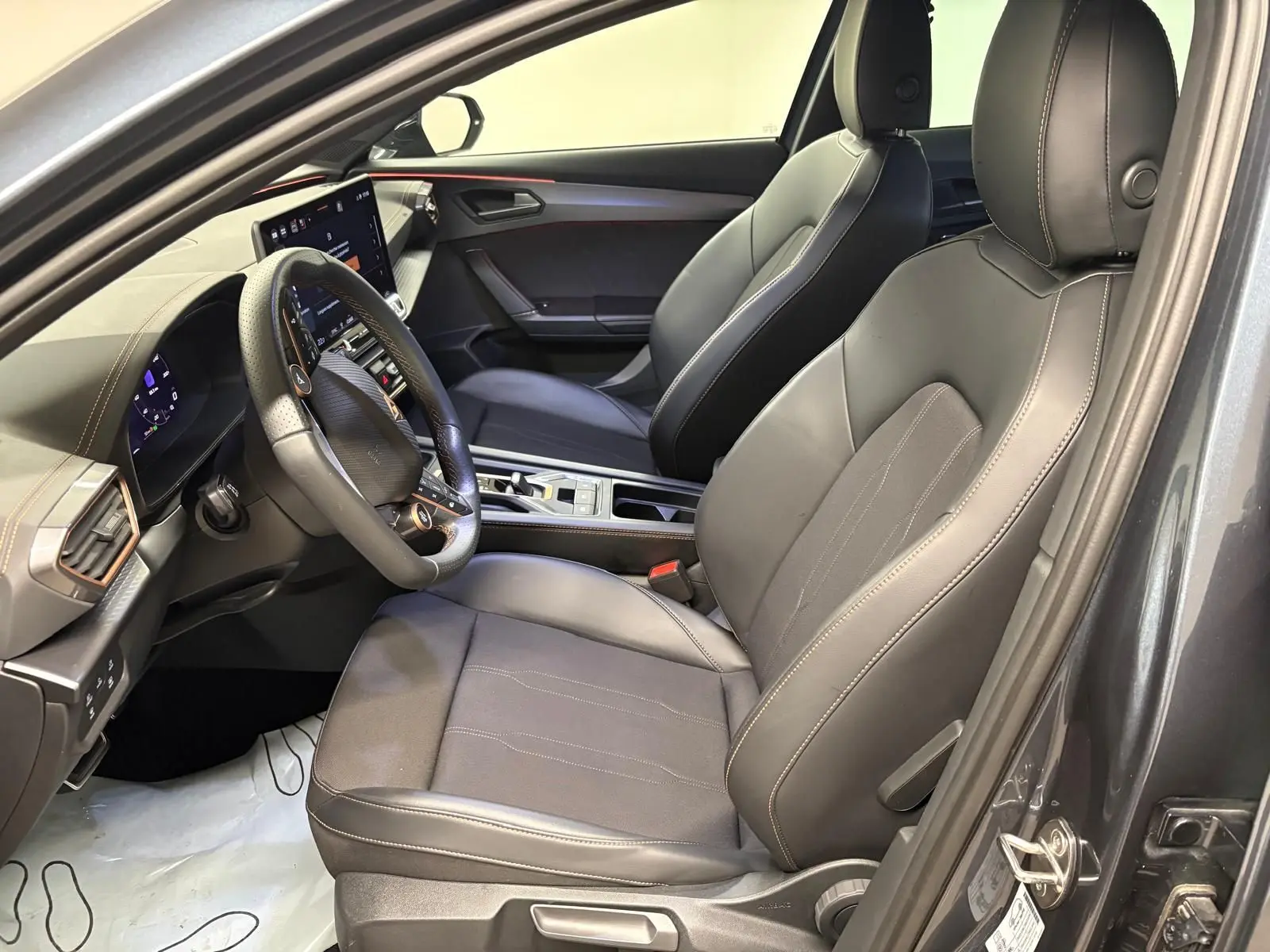 Vue intérieure côté conducteur du CUPRA Formentor gris magnétique, avec sièges en cuir noir et tableau de bord moderne.