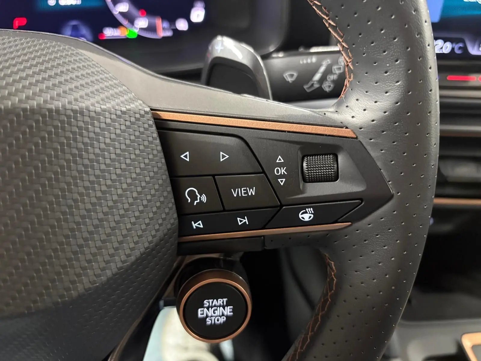 Gros plan sur le volant perforé et les commandes multifonctions du CUPRA Formentor gris magnétique, avec bouton start/stop visible.