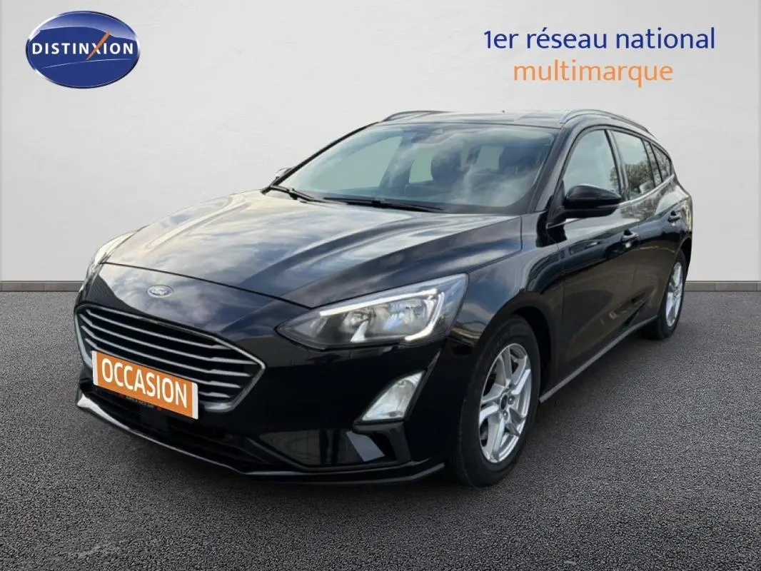 Ford Focus SW noire vue en 3/4 avant droit avec barres de toit et jantes alliage 16 pouces.
