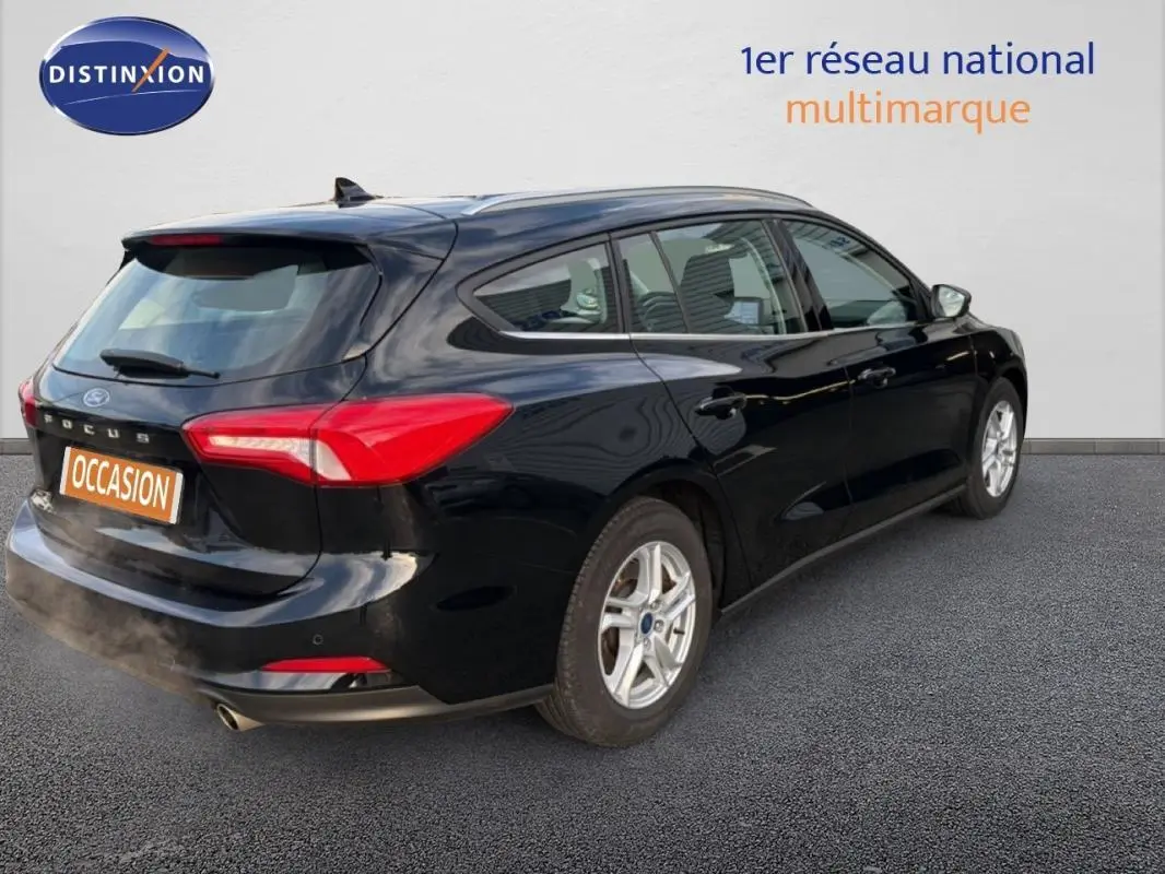 Ford Focus SW noire vue en 3/4 arrière droit, avec barres de toit et jantes alliage 16 pouces.