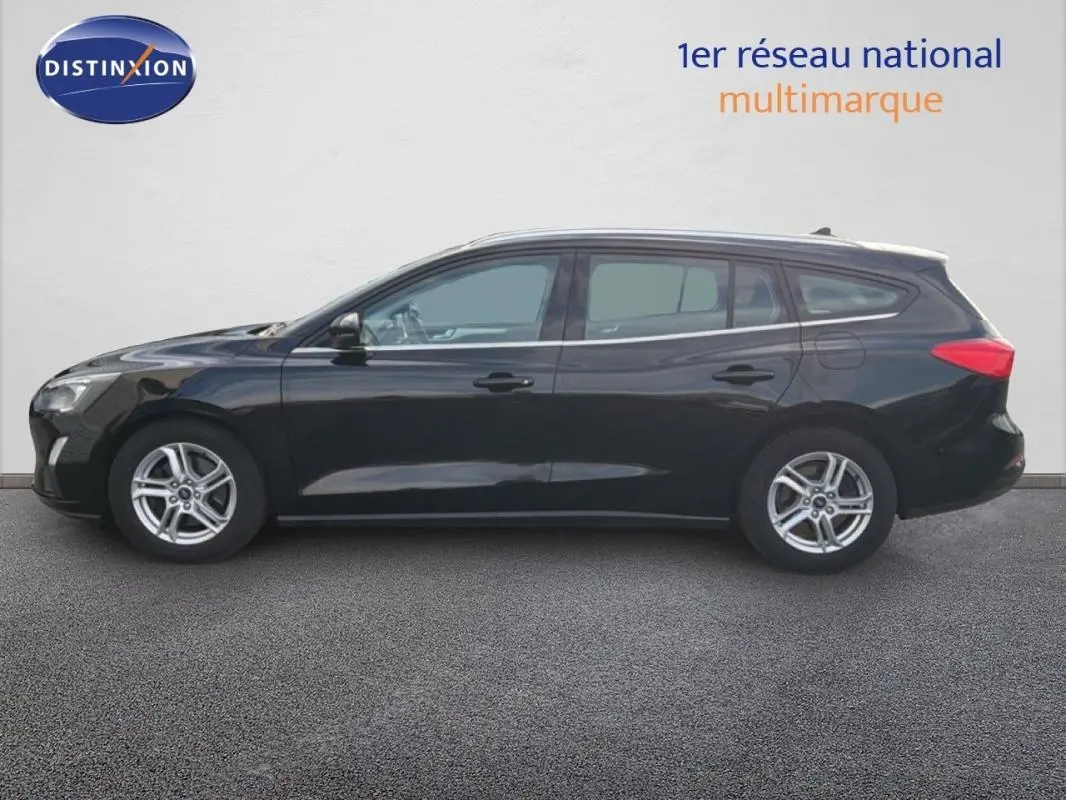 Profil côté gauche d'une Ford Focus SW noire de 2019 avec jantes alliage 16 pouces et barres de toit visibles.