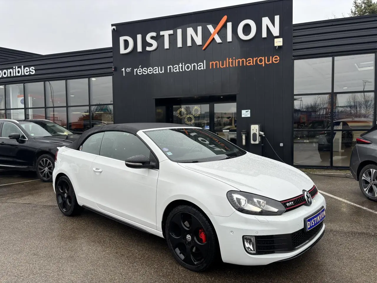 Volkswagen Golf VI Cabriolet blanc vue 3/4 avant avec toit noir et jantes noires distinctives.