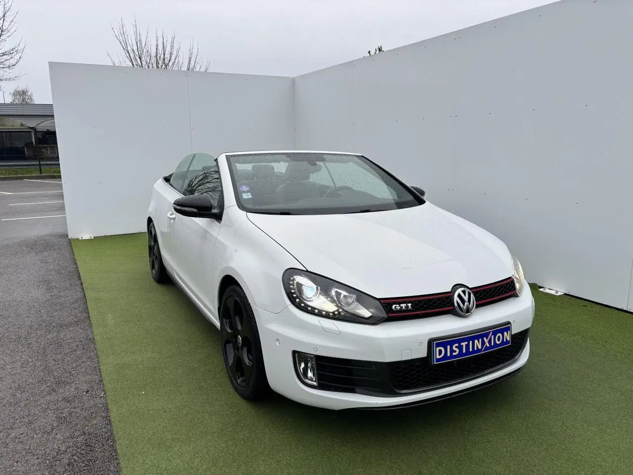 Volkswagen Golf VI Cabriolet blanc vue 3/4 avant avec jantes noires et calandre GTI rouge