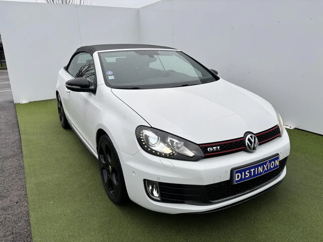 Volkswagen Golf VI Cabriolet blanc vue 3/4 avant avec toit souple noir et jantes alliage noires.