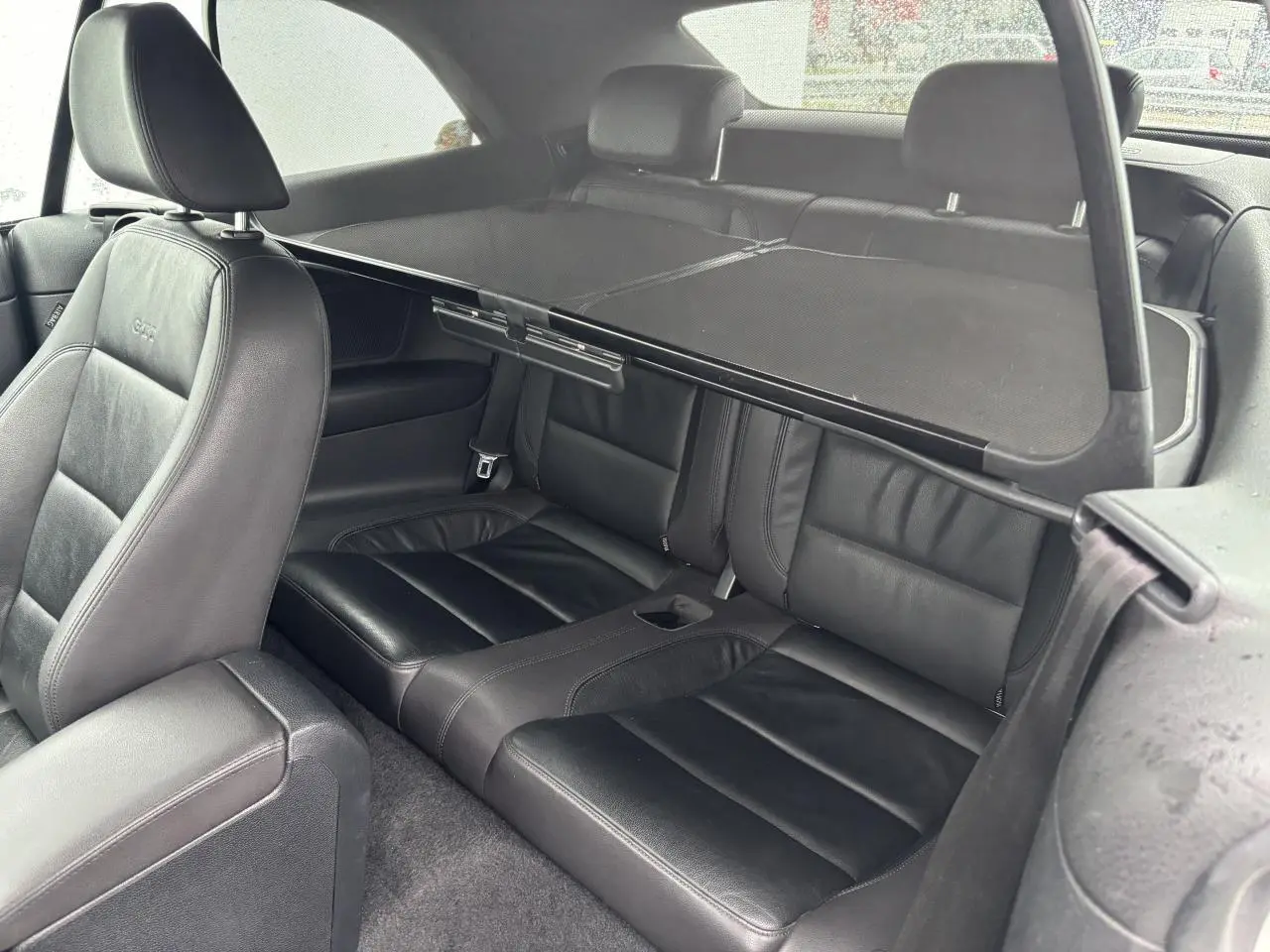 Vue intérieure côté arrière droit de la Volkswagen Golf VI Cabriolet avec sièges en cuir noir et filet anti-remous.