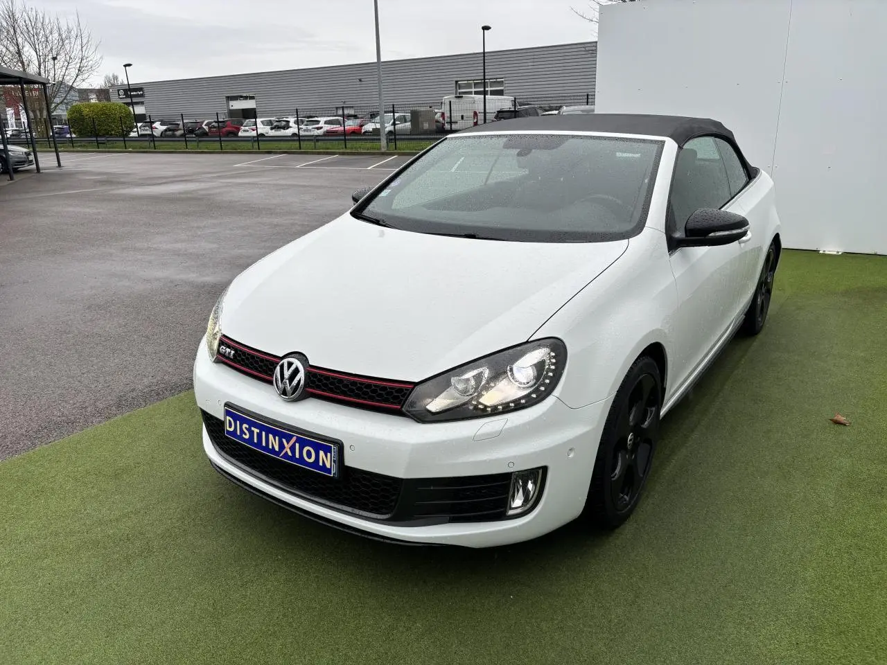 Volkswagen Golf VI Cabriolet blanc vue 3/4 avant droit avec toit souple noir et jantes noires.