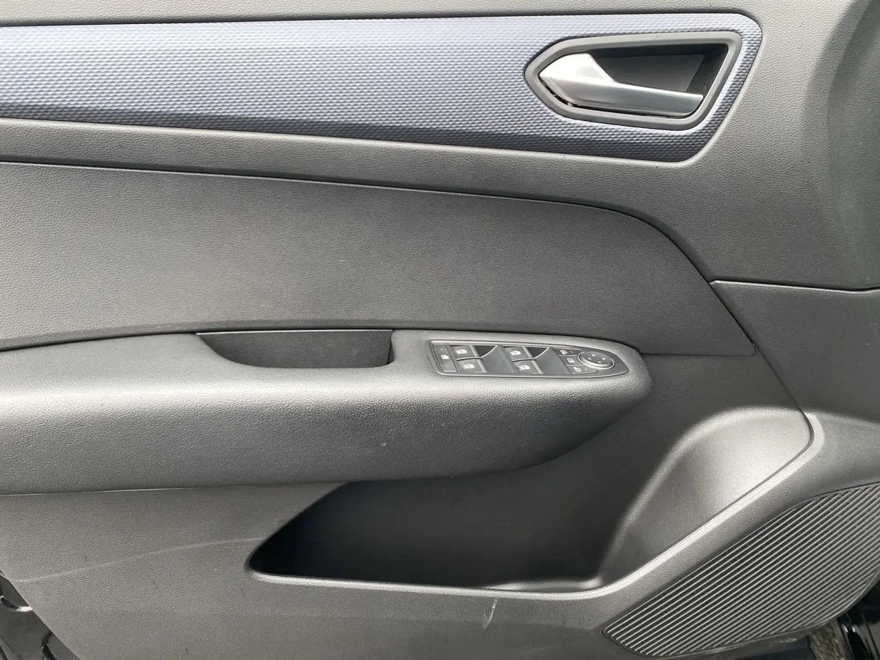 Intérieur de la porte côté gauche d’une Renault Arkana noire 2024, avec commandes de vitres et poignée argentée.